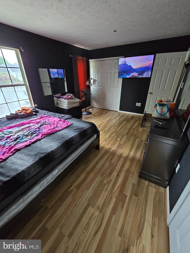 bedroom with wood-type flooring, a textured ceiling, and a closet