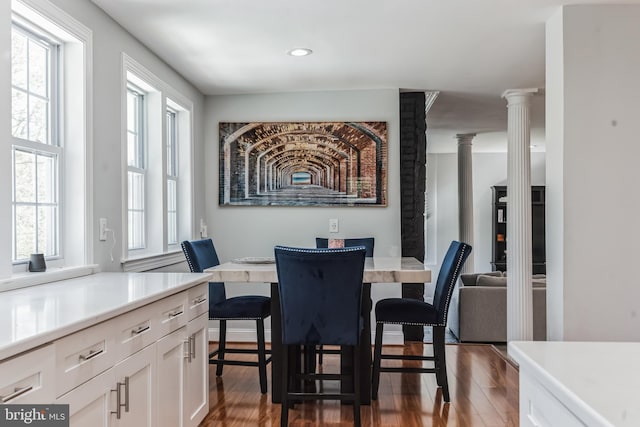 dining room featuring a wealth of natural light, dark hardwood / wood-style flooring, and decorative columns