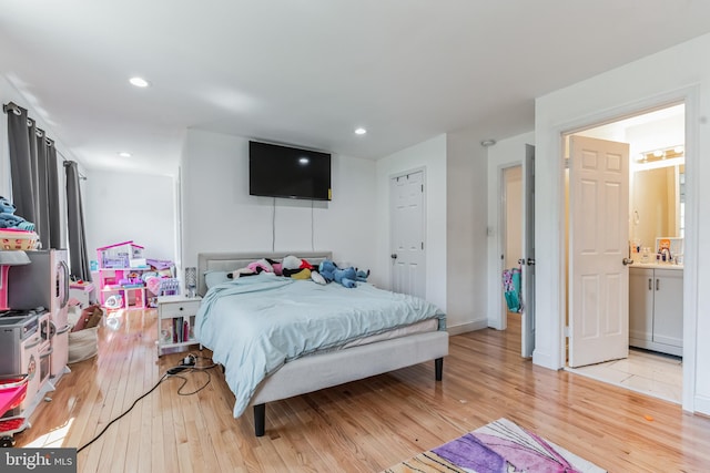 bedroom with ensuite bath, sink, and light hardwood / wood-style floors