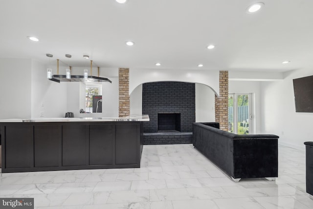 kitchen featuring light tile flooring, light stone countertops, brick wall, and a brick fireplace