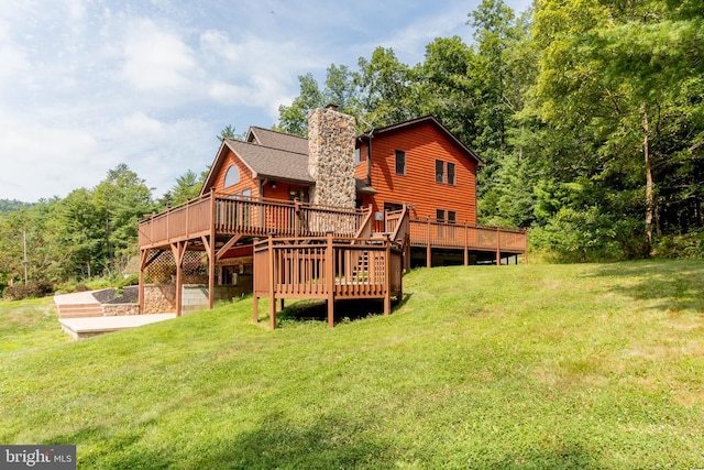 rear view of house with a wooden deck, a patio area, and a yard