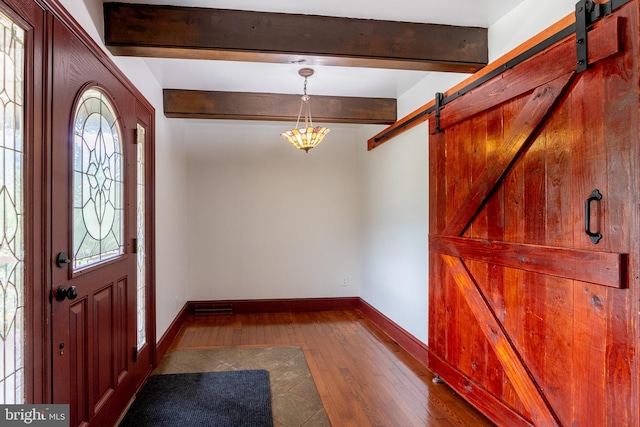 foyer featuring beam ceiling, a barn door, and hardwood / wood-style flooring