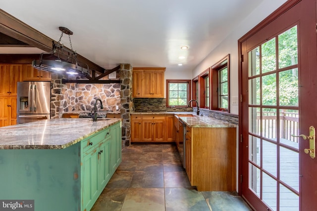 kitchen with backsplash, sink, hanging light fixtures, stainless steel fridge with ice dispenser, and light stone counters