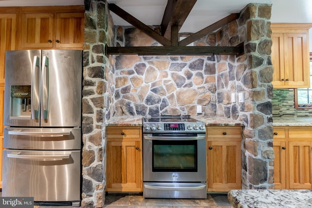 kitchen with beam ceiling, appliances with stainless steel finishes, and light stone counters