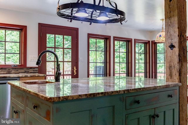 kitchen with decorative light fixtures, dishwasher, sink, and light stone counters