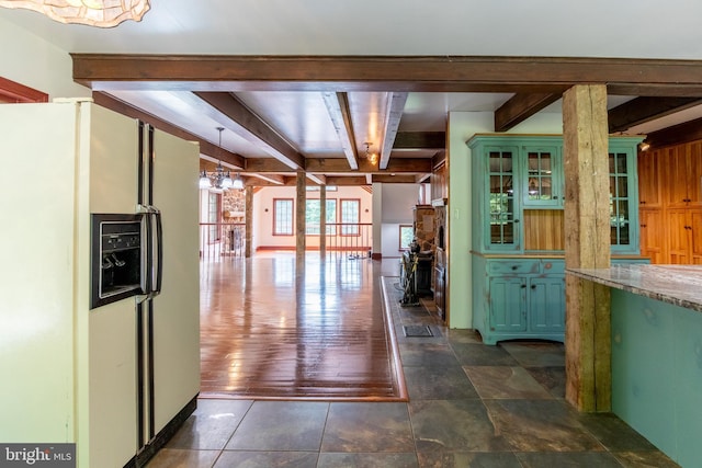 kitchen with pendant lighting, beamed ceiling, white refrigerator with ice dispenser, green cabinetry, and light stone counters