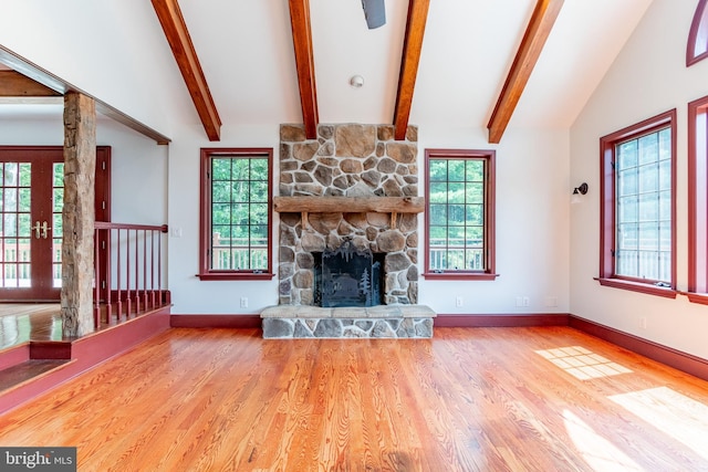 unfurnished living room with lofted ceiling, wood-type flooring, and a stone fireplace