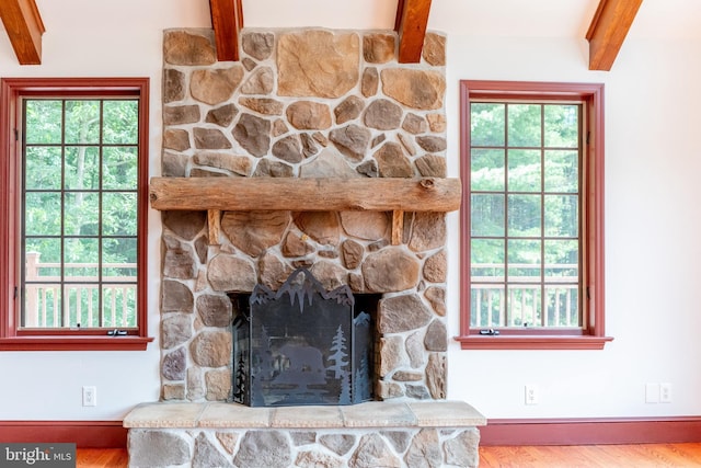 interior details featuring beam ceiling, hardwood / wood-style flooring, and a stone fireplace