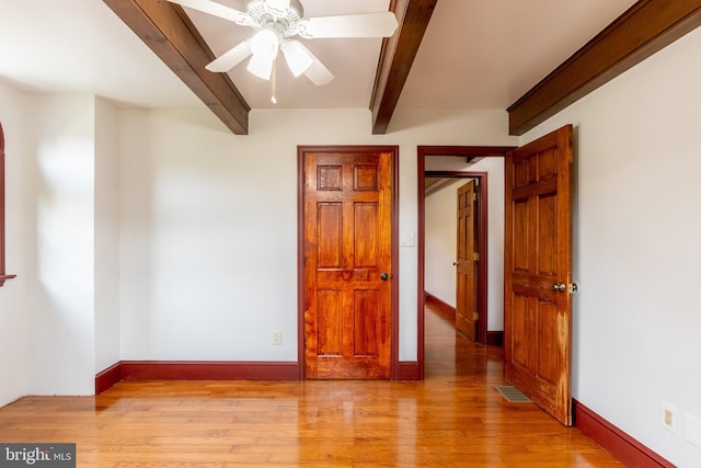 empty room with ceiling fan, light hardwood / wood-style floors, and beam ceiling