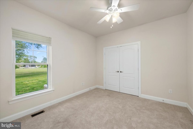 unfurnished bedroom featuring ceiling fan, multiple windows, and light carpet