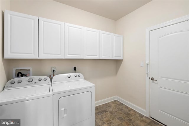 laundry room featuring dark tile patterned floors, washer and clothes dryer, and cabinets