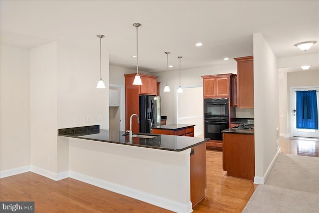 kitchen with light hardwood / wood-style floors, sink, decorative light fixtures, kitchen peninsula, and black appliances