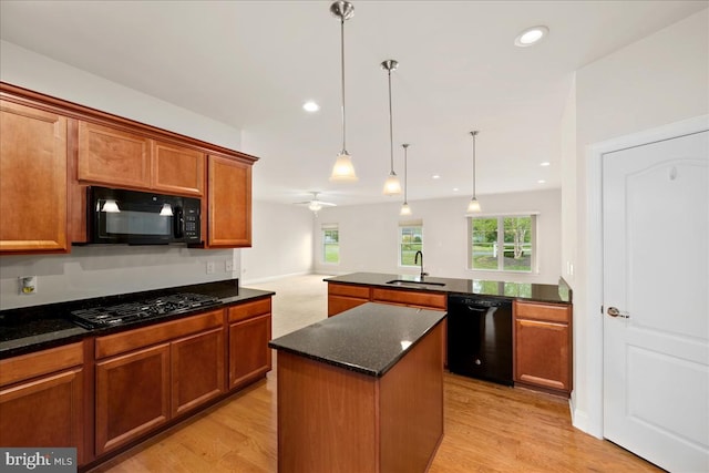 kitchen featuring sink, light wood-type flooring, black appliances, and a kitchen island