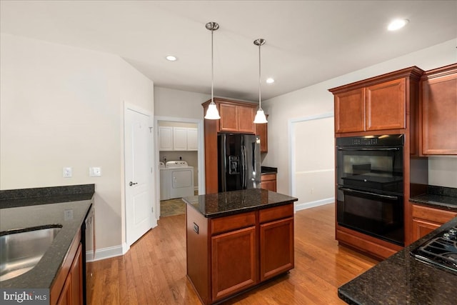 kitchen featuring independent washer and dryer, decorative light fixtures, black appliances, and light wood-type flooring