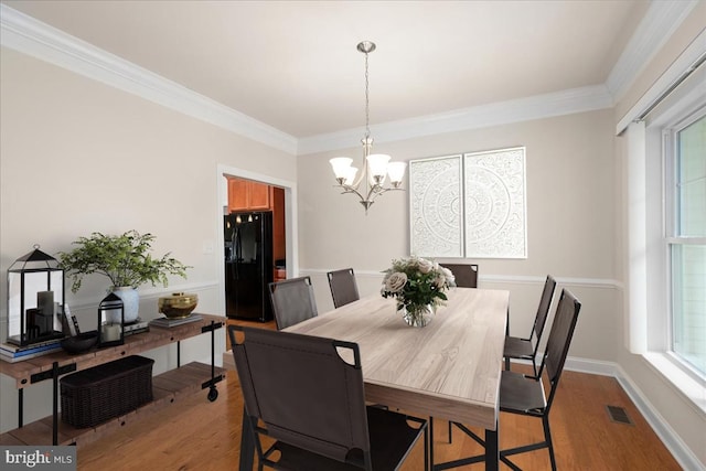 dining space featuring light hardwood / wood-style floors, a notable chandelier, and ornamental molding