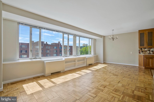 empty room featuring radiator heating unit, light parquet floors, and a notable chandelier