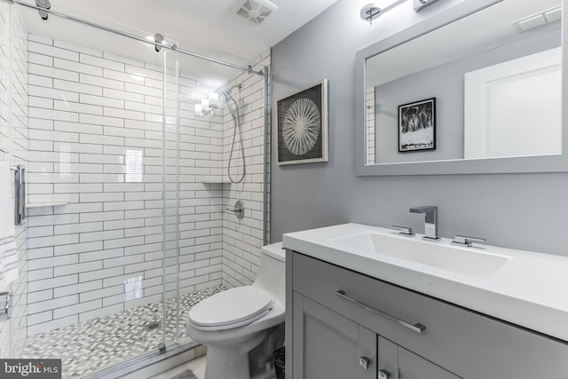 bathroom with a shower with shower door, toilet, and vanity