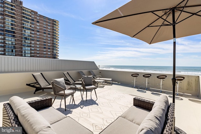 view of terrace with a view of the beach, a water view, a balcony, and outdoor lounge area