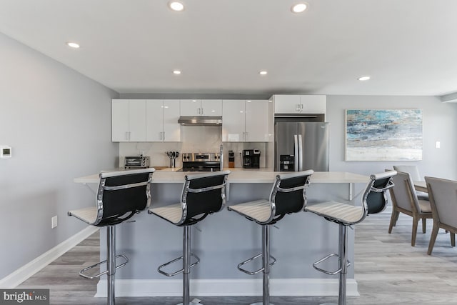 kitchen with stainless steel fridge with ice dispenser, white cabinets, and a breakfast bar area