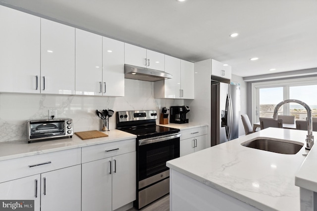 kitchen with white cabinetry, backsplash, stainless steel appliances, light stone counters, and sink