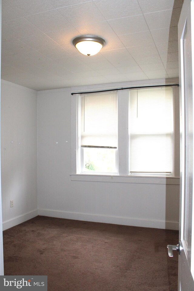 unfurnished room with dark colored carpet