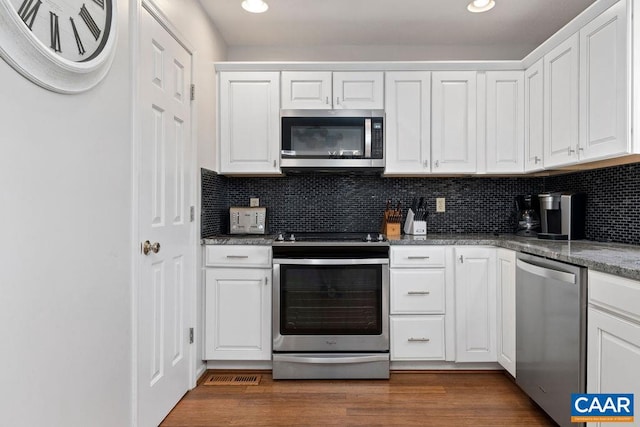 kitchen with appliances with stainless steel finishes, dark wood-type flooring, white cabinets, and dark stone countertops