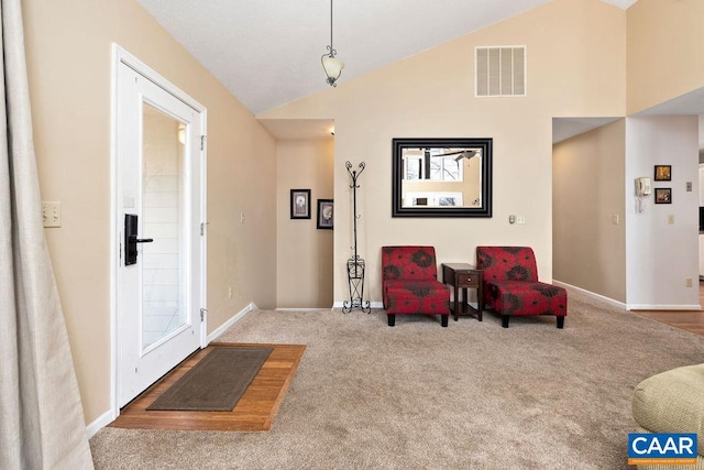 carpeted foyer featuring high vaulted ceiling