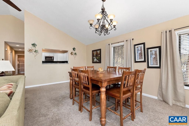 dining area featuring light colored carpet, lofted ceiling, and a chandelier