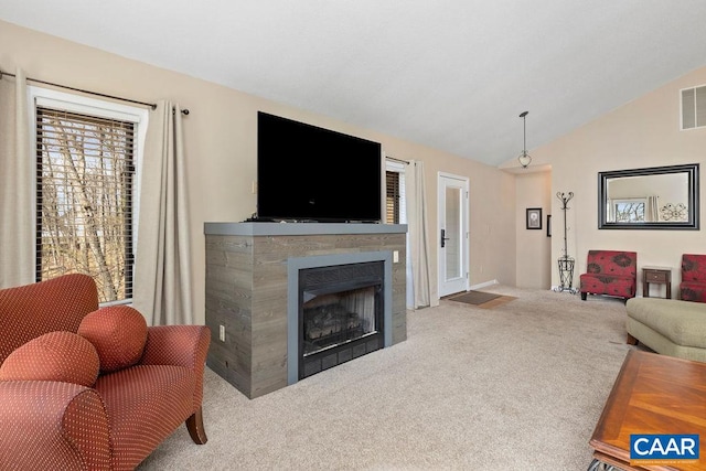 living room featuring light colored carpet, a tiled fireplace, and vaulted ceiling