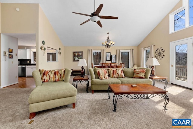 carpeted living room with high vaulted ceiling and ceiling fan with notable chandelier