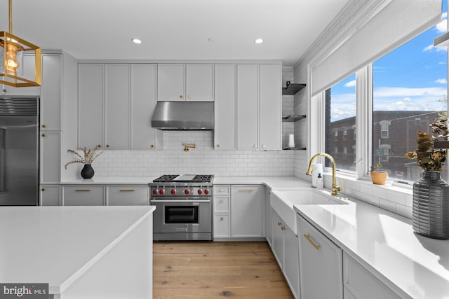 kitchen featuring pendant lighting, white cabinets, light wood-type flooring, backsplash, and high quality appliances