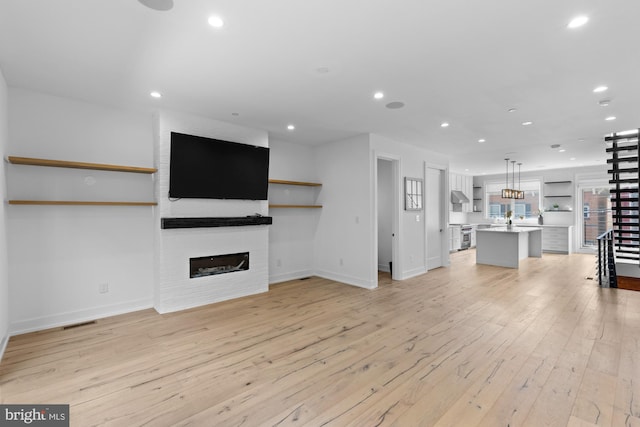 unfurnished living room with brick wall, light hardwood / wood-style flooring, and a fireplace