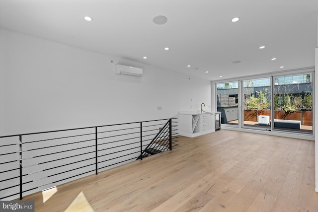 hall featuring sink, light hardwood / wood-style flooring, and a wall unit AC