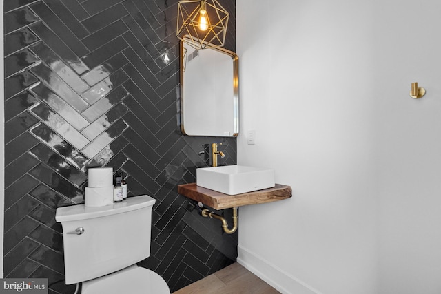 bathroom featuring toilet, tile walls, and sink