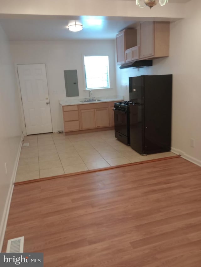 kitchen with sink, light brown cabinets, light tile floors, and black appliances