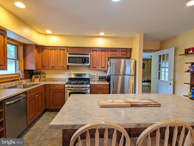 kitchen with a healthy amount of sunlight, dark tile flooring, stainless steel appliances, and sink