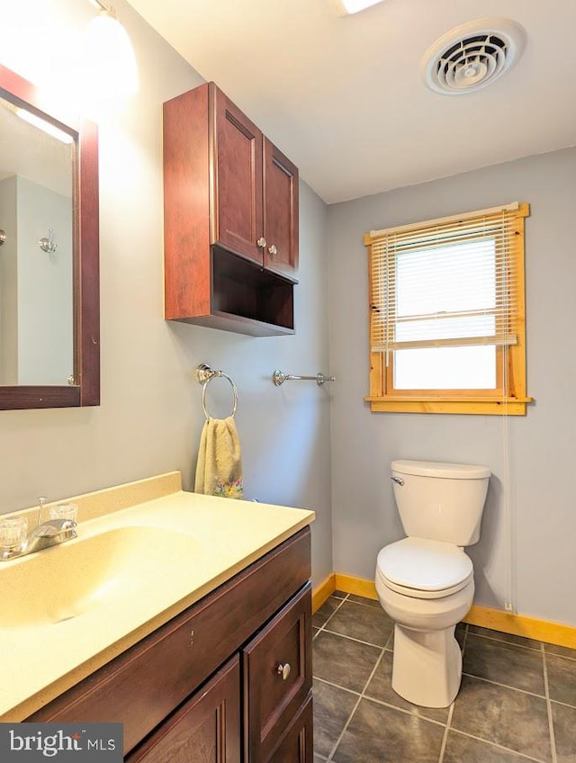 bathroom with toilet, vanity with extensive cabinet space, and tile flooring