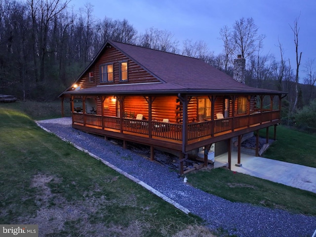 log cabin with a wooden deck and a lawn