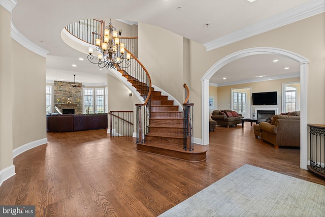 entrance foyer with hardwood / wood-style flooring, a stone fireplace, decorative columns, and ornamental molding