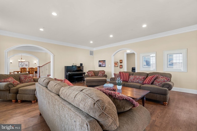 living room featuring a chandelier, dark wood-type flooring, and ornamental molding