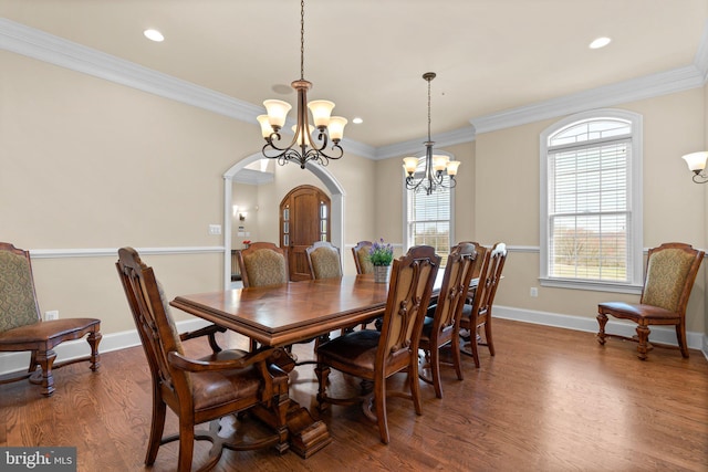 dining room with hardwood / wood-style flooring, crown molding, and a notable chandelier