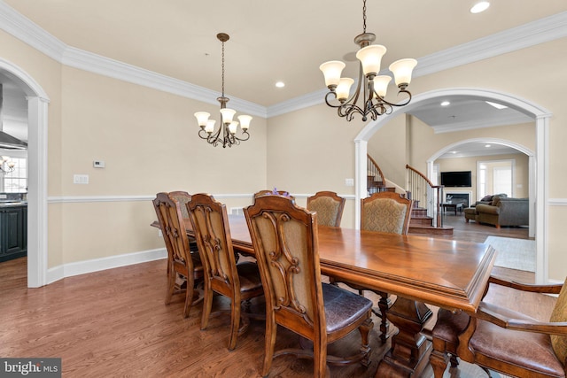 dining space featuring wood-type flooring, ornamental molding, and a chandelier