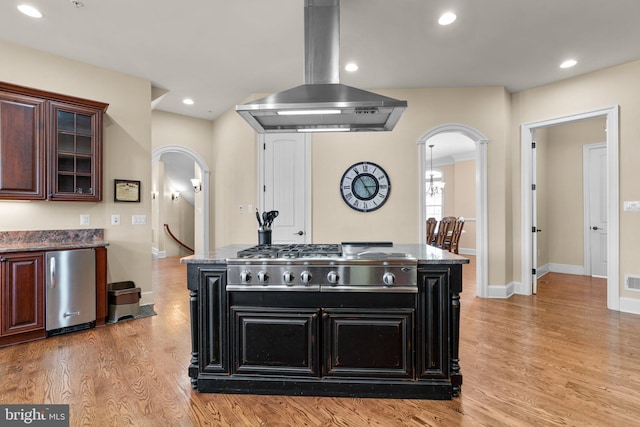 kitchen with island exhaust hood, a center island, light wood-type flooring, and stainless steel appliances