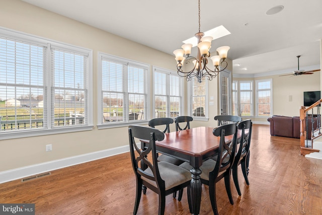 dining area featuring hardwood / wood-style floors, ceiling fan with notable chandelier, and plenty of natural light