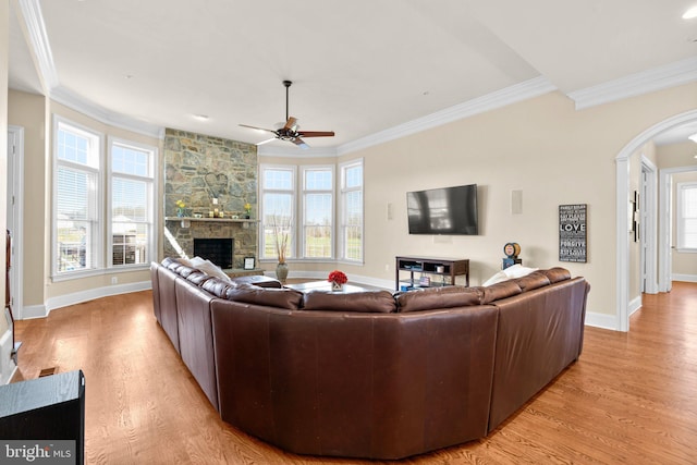 living room featuring ceiling fan, light hardwood / wood-style floors, ornamental molding, and a fireplace