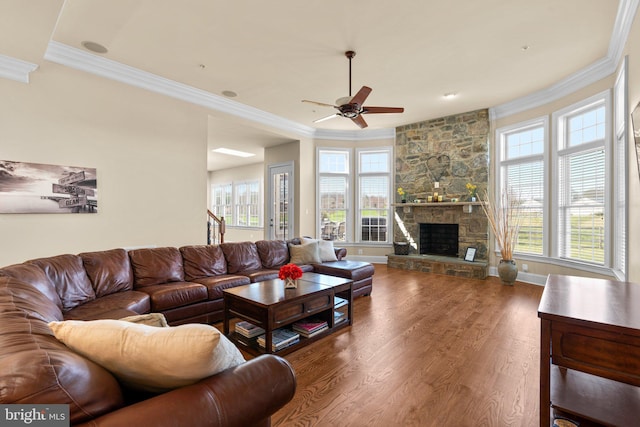 living room with ceiling fan, a fireplace, wood-type flooring, and ornamental molding