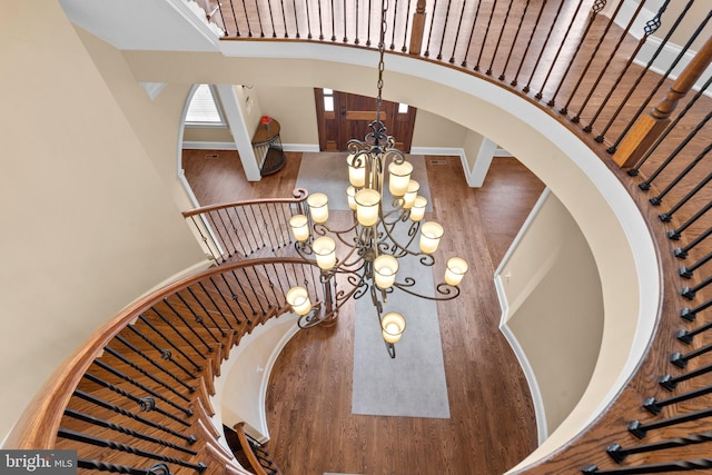 stairway with a chandelier, a high ceiling, and hardwood / wood-style flooring