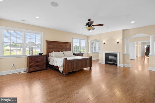 bedroom featuring ornate columns, ceiling fan, and light wood-type flooring