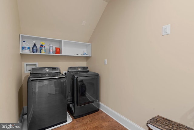 washroom with washing machine and clothes dryer and hardwood / wood-style floors