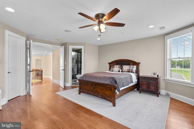 bedroom with ensuite bath, ceiling fan, and light hardwood / wood-style floors